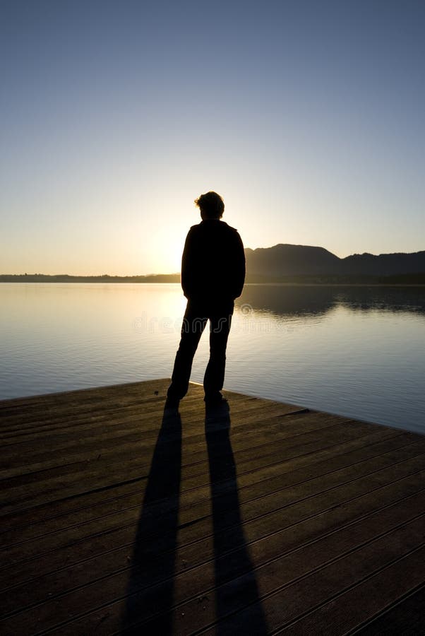 - a person against sunrise on a peer in Bavaria, Germany. - a person against sunrise on a peer in Bavaria, Germany