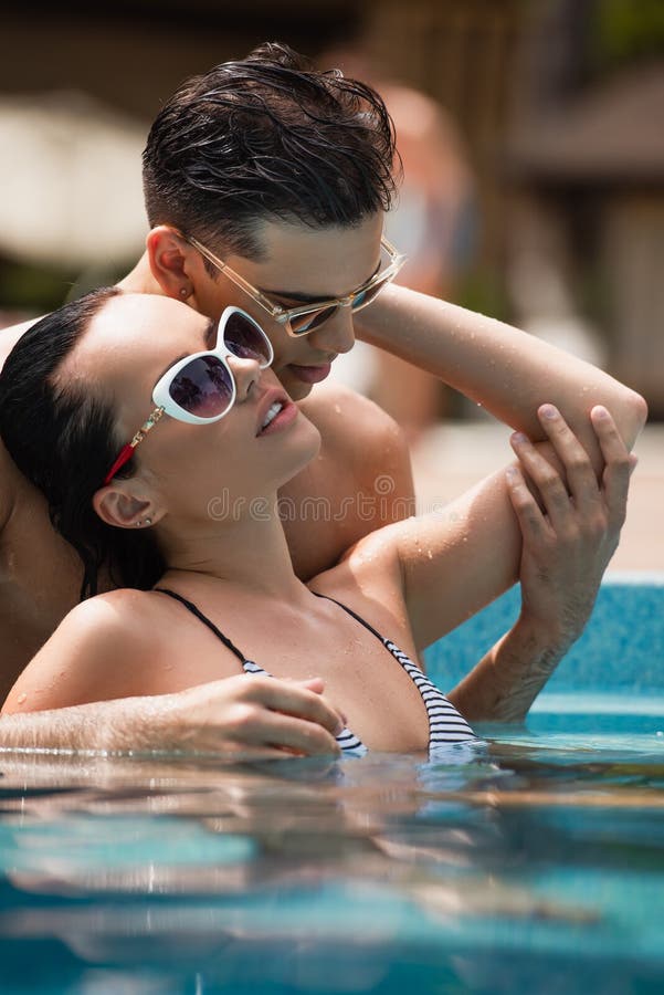Surface level of men touching hand of sexy girlfriend in swimming pool,stock image. Surface level of men touching hand of sexy girlfriend in swimming pool,stock image