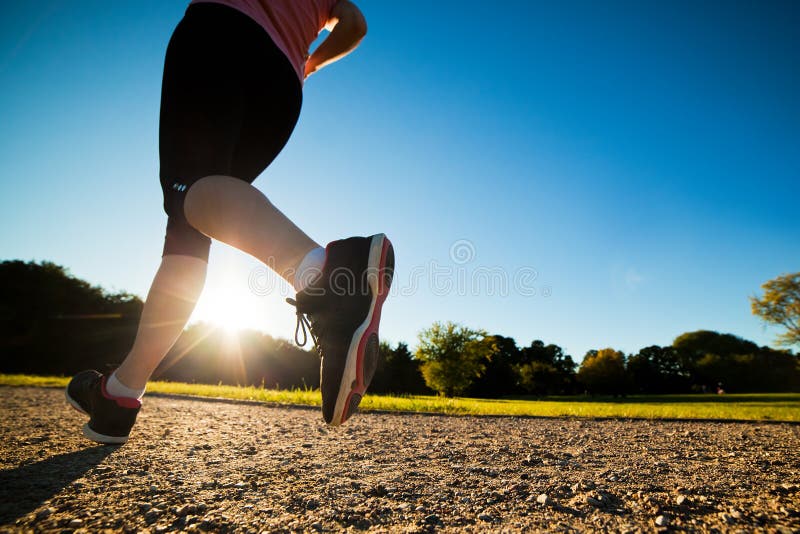 Young fit woman does running, jogging training in a park at summer sunny day. Legs close up. Young fit woman does running, jogging training in a park at summer sunny day. Legs close up