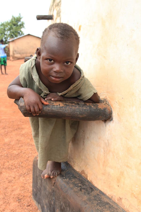 Larabanga muslim village in northern Ghana, Western Africa, A boy looks with curiosity into a lens. He poses on the walls of a historical clay mosque which is one of the most important tourist attraction in the area. Located at the edge of the famous Mole National Park Larabanga is one of the most touristic places in Ghana. In effect, Larabange has undergone drastic and apparently negative changes in recent years. This is not architecture that has changed, but psyche of people. In the past a calm dusty village on Sahel, nowadays Larabanga besides its traditional architecture offers tourists a lot of hassle. The problem is openly discussed in international guidebooks and internet forums. Larabanga muslim village in northern Ghana, Western Africa, A boy looks with curiosity into a lens. He poses on the walls of a historical clay mosque which is one of the most important tourist attraction in the area. Located at the edge of the famous Mole National Park Larabanga is one of the most touristic places in Ghana. In effect, Larabange has undergone drastic and apparently negative changes in recent years. This is not architecture that has changed, but psyche of people. In the past a calm dusty village on Sahel, nowadays Larabanga besides its traditional architecture offers tourists a lot of hassle. The problem is openly discussed in international guidebooks and internet forums.