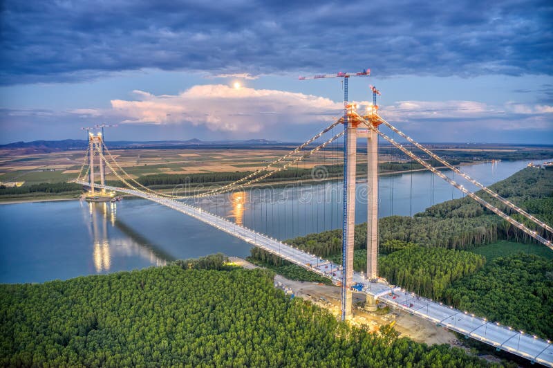 Panoramic aerial drone view from above of the suspended bridge over danube river, under construction, between Braila and Tulcea cities in Romania. Panoramic aerial drone view from above of the suspended bridge over danube river, under construction, between Braila and Tulcea cities in Romania.