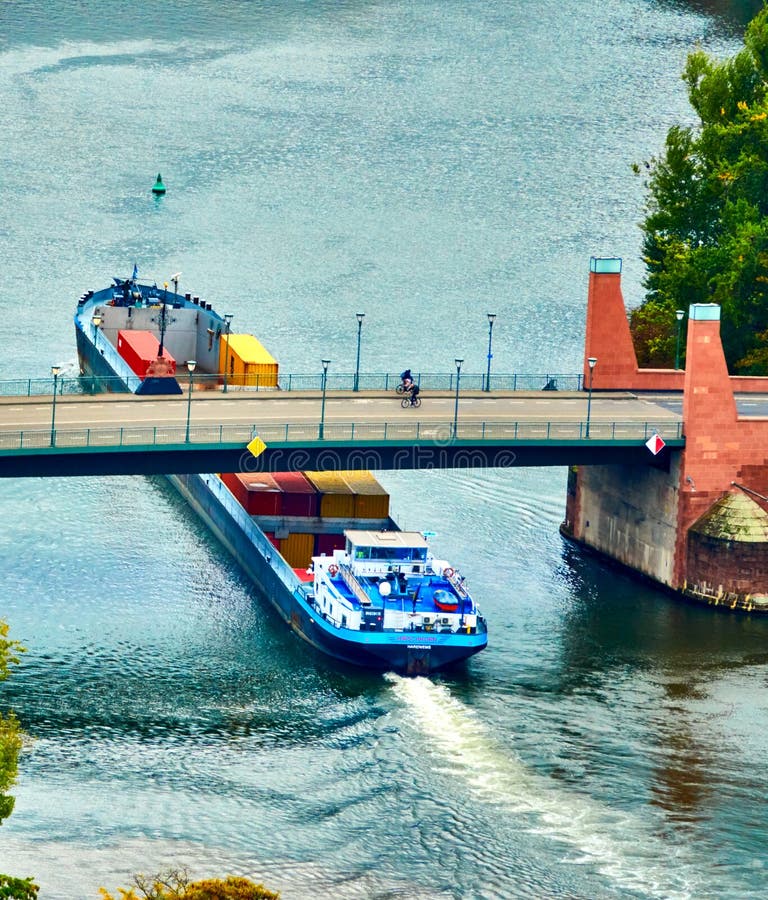 Frankfurt, Germany, October 2., 2019: Aerial view of a cargo ship loaded with containers passing under a bridge over the Main River in downtown Frankfurt, Germany. Frankfurt, Germany, October 2., 2019: Aerial view of a cargo ship loaded with containers passing under a bridge over the Main River in downtown Frankfurt, Germany