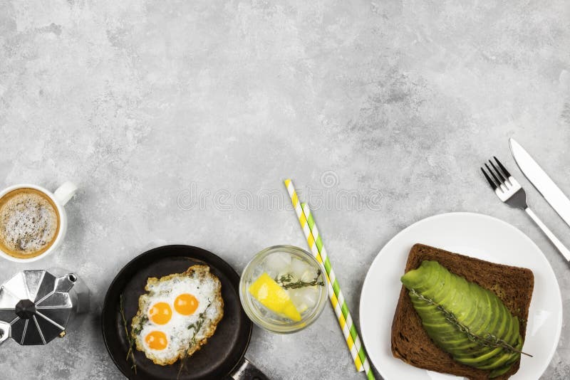传统早餐-从黑麦面包敬酒用鲕梨，从鹌鹑蛋，在轻的背景的柠檬水的煎蛋 顶视图