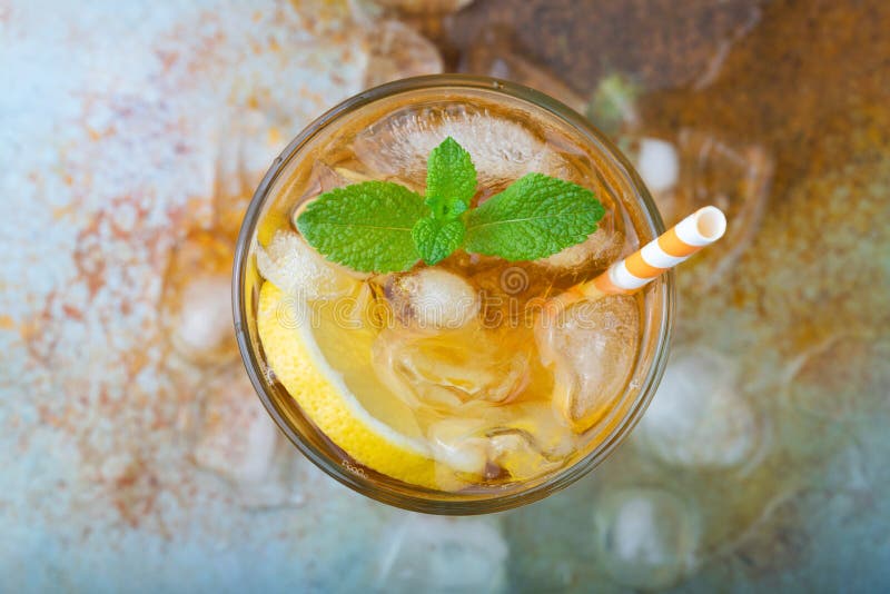 Traditional iced tea with lemon, mint and ice in tall glasses. A glass of refreshing summer drink on the old rusty background. Top view. Traditional iced tea with lemon, mint and ice in tall glasses. A glass of refreshing summer drink on the old rusty background. Top view.