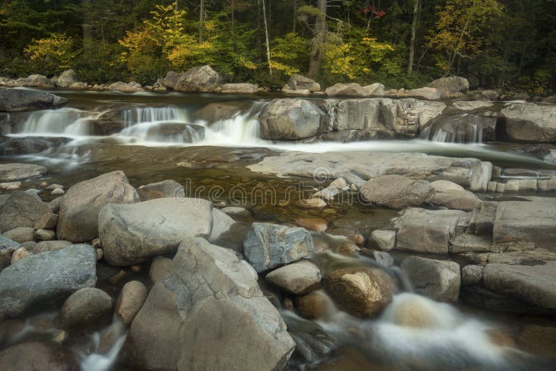 Small drop over granite and rapids in long exposure among boulders at Lower Falls of the Swift River in the White Mountains National Forest of New Hampshire. Small drop over granite and rapids in long exposure among boulders at Lower Falls of the Swift River in the White Mountains National Forest of New Hampshire.