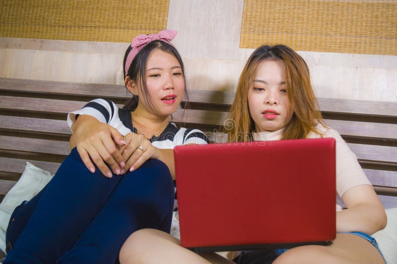 使用互联网社会媒介的两间年轻俏丽和愉快的亚洲韩国学生女孩一起在家卧室在手提电脑 免版税库存照片 使用互联网社会媒介的两间年轻俏丽和愉快的亚洲韩国学生女孩一起在家卧室在手提电脑 免版税库存照片