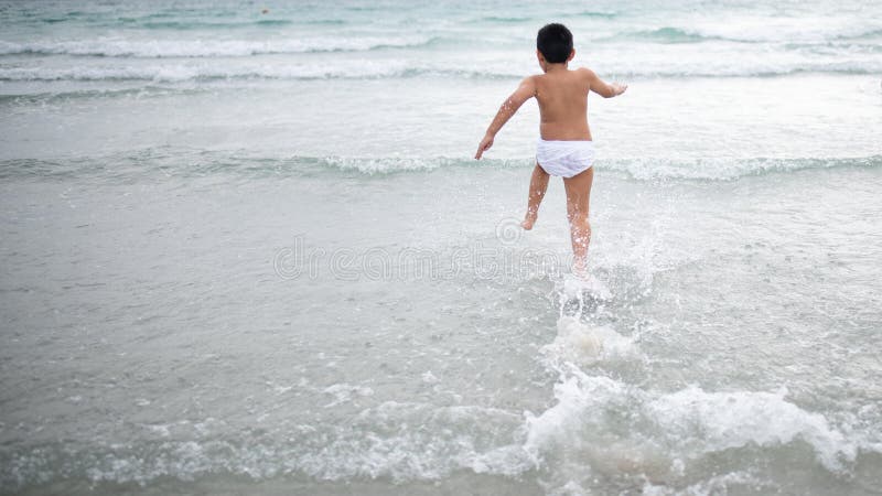 使用在沙滩的男孩 愉快的孩子在度假在海边在度假夏天休假 孩子本质上与海、沙子和天空蔚蓝的 库存照片
