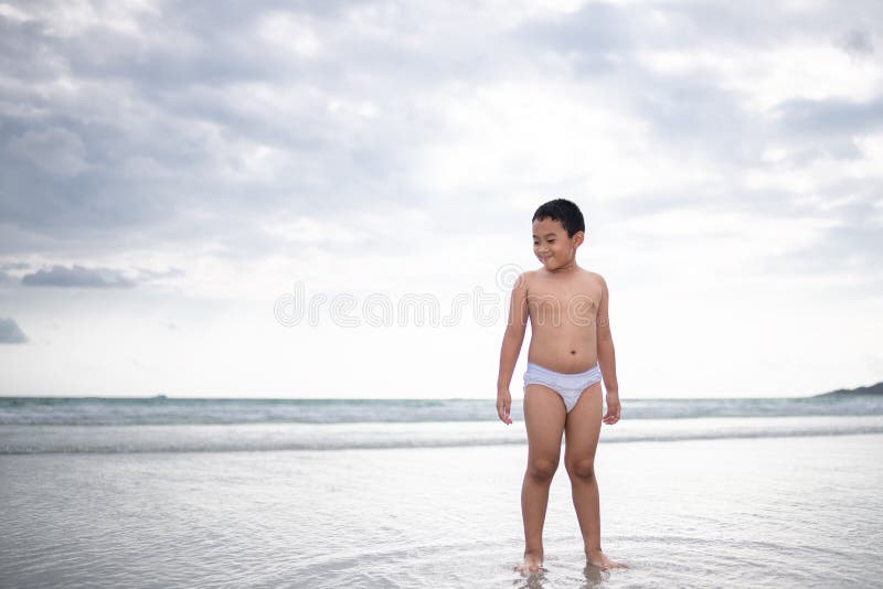 使用在沙滩的男孩 愉快的孩子在度假在海边在度假夏天休假 孩子本质上与海、沙子和天空蔚蓝的 免版税库存图片