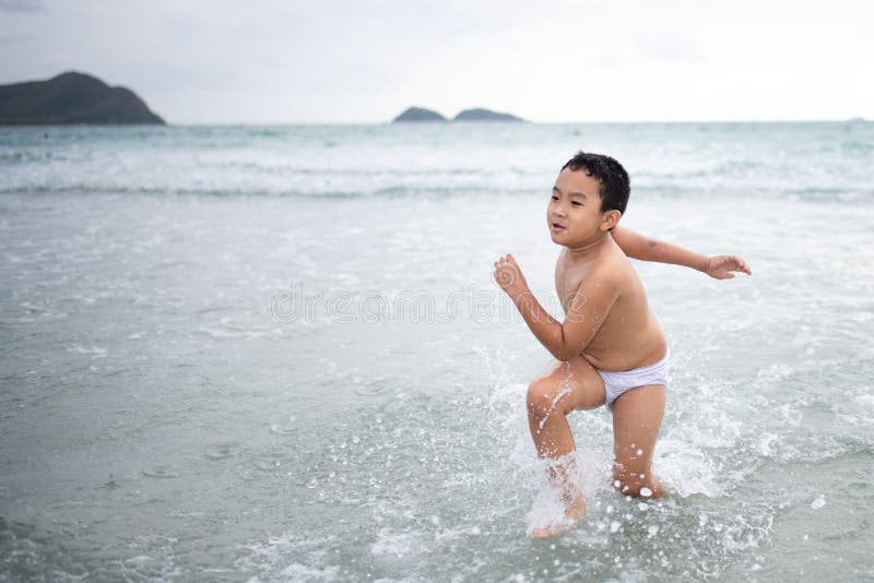 使用在沙滩的男孩 愉快的孩子在度假在海边在度假夏天休假 孩子本质上与海、沙子和天空蔚蓝的 库存图片