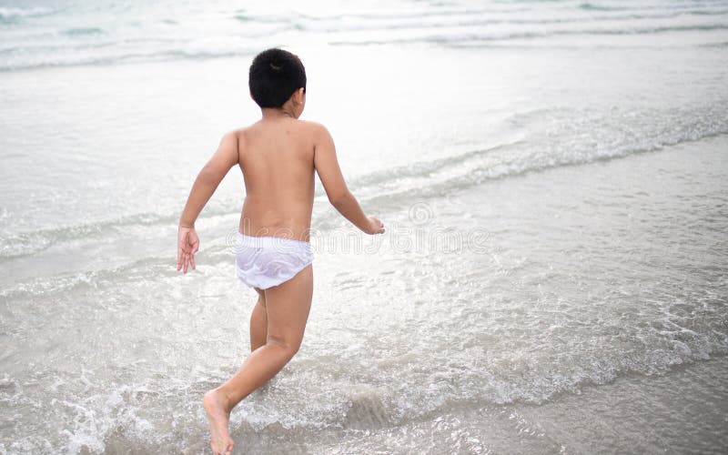 使用在沙滩的男孩 愉快的孩子在度假在海边在度假夏天休假 孩子本质上与海、沙子和天空蔚蓝的 免版税库存照片