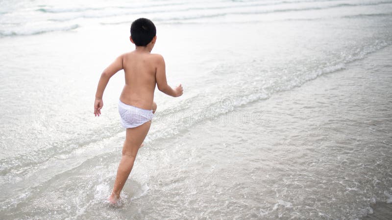使用在沙滩的男孩 愉快的孩子在度假在海边在度假夏天休假 孩子本质上与海、沙子和天空蔚蓝的 库存图片