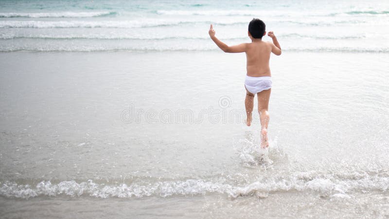 使用在沙滩的男孩 愉快的孩子在度假在海边在度假夏天休假 孩子本质上与海、沙子和天空蔚蓝的 库存图片