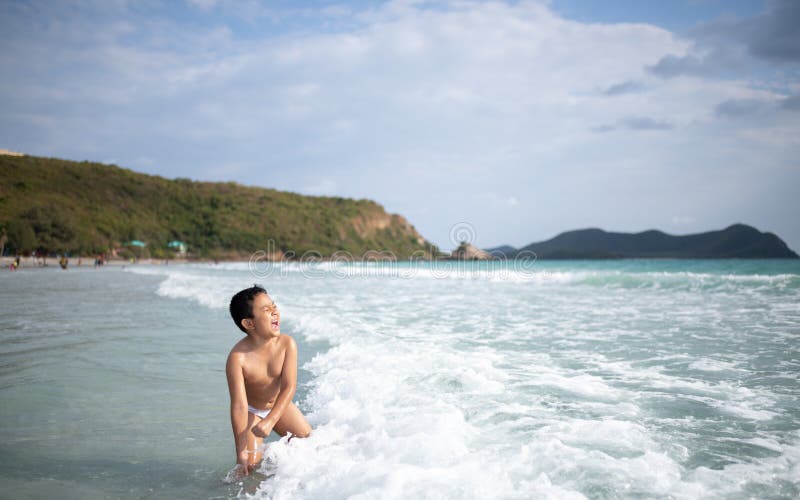 使用在沙滩的男孩 愉快的孩子在度假在海边在度假夏天休假 孩子本质上与海、沙子和天空蔚蓝的 免版税库存图片