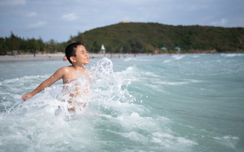 使用在沙滩的男孩 愉快的孩子在度假在海边在度假夏天休假 孩子本质上与海、沙子和天空蔚蓝的 免版税库存照片