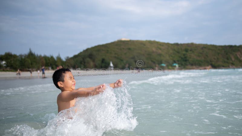 使用在沙滩的男孩 愉快的孩子在度假在海边在度假夏天休假 孩子本质上与海、沙子和天空蔚蓝的 免版税库存图片