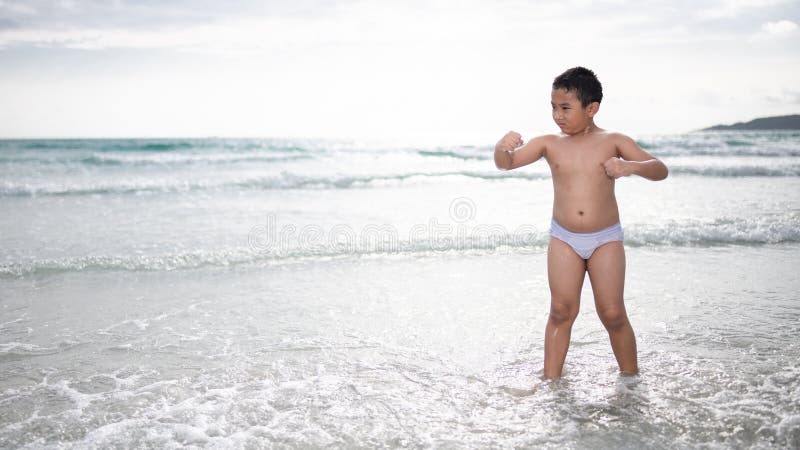 使用在沙滩的男孩 愉快的孩子在度假在海边在度假夏天休假 孩子本质上与海、沙子和天空蔚蓝的 免版税库存照片