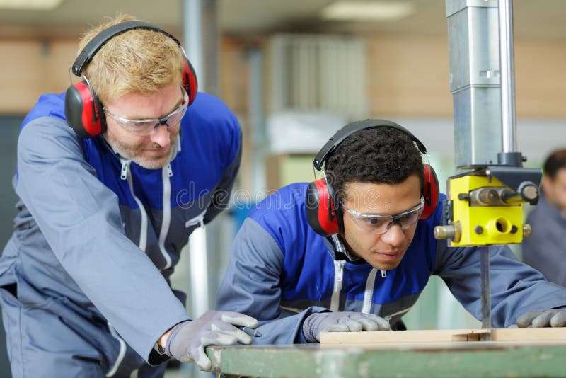 学徒木匠在监督下使用带锯 免版税库存照片