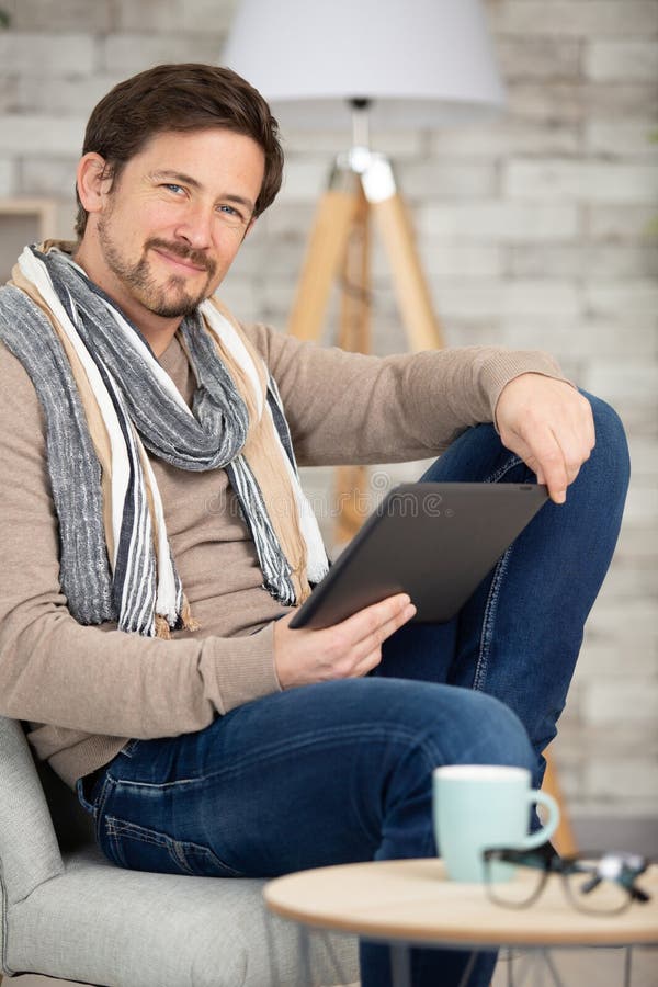 young man relaxing on sofa using tablet computer indoors. young man relaxing on sofa using tablet computer indoors