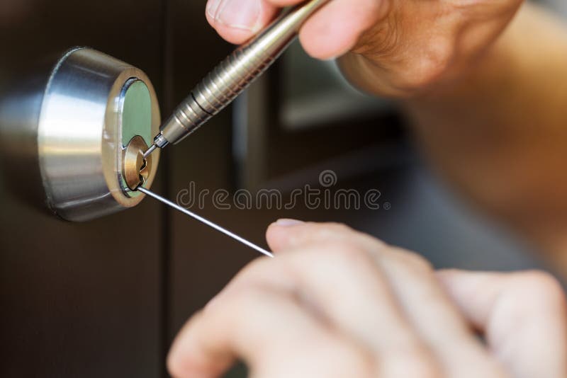 使用打开采撷的工具的锁匠手锁着的门 库存图片 使用打开采撷的工具的锁匠手锁着的门 库存图片