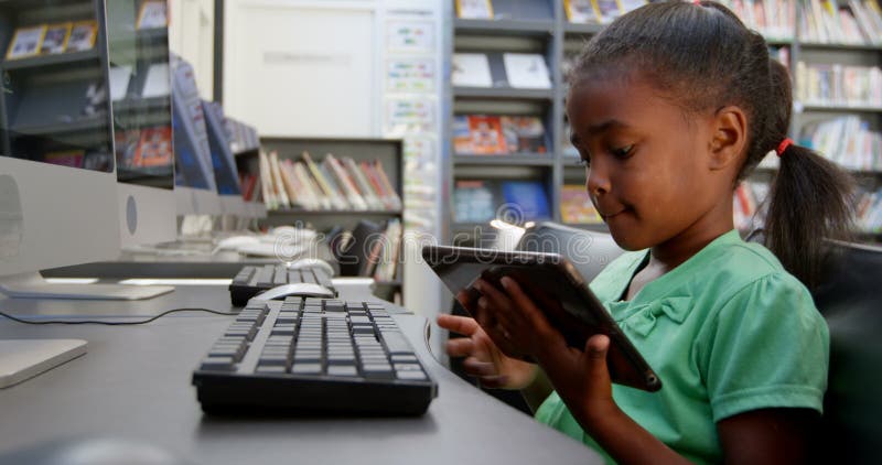 使用数字片剂的非裔美国人的女小学生侧视图在图书馆在学校4k