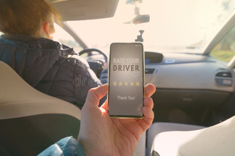 Passenger is sitting on the back seat of the car and using smart phone app to rate a driver. Taxi or modern peer to peer ridesharing concept. Passenger is sitting on the back seat of the car and using smart phone app to rate a driver. Taxi or modern peer to peer ridesharing concept