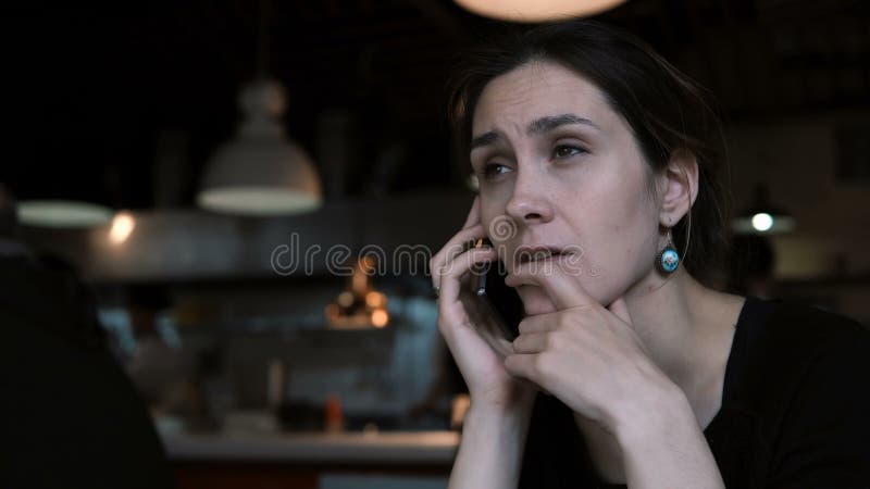 使用智能手机的美丽的少妇，当等待命令在咖啡馆时 女性谈话在手机