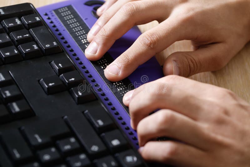 Blind person using computer with braille computer display and a computer keyboard. Blindness aid, visual impairment, independent life concept. Blind person using computer with braille computer display and a computer keyboard. Blindness aid, visual impairment, independent life concept.