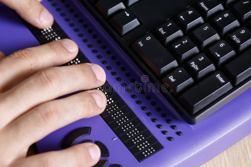 Blind person using computer with braille computer display and a computer keyboard. Blindness aid, visual impairment, independent life concept. Blind person using computer with braille computer display and a computer keyboard. Blindness aid, visual impairment, independent life concept.