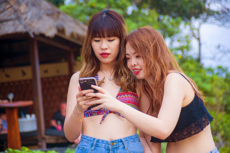 使用流动酸碱度的,互联网两愉快和相当享受暑假的亚裔韩国女朋友一起绊倒在热带海滩 库存图片 使用流动酸碱度的,互联网两愉快和相当享受暑假的亚裔韩国女朋友一起绊倒在热带海滩 库存图片