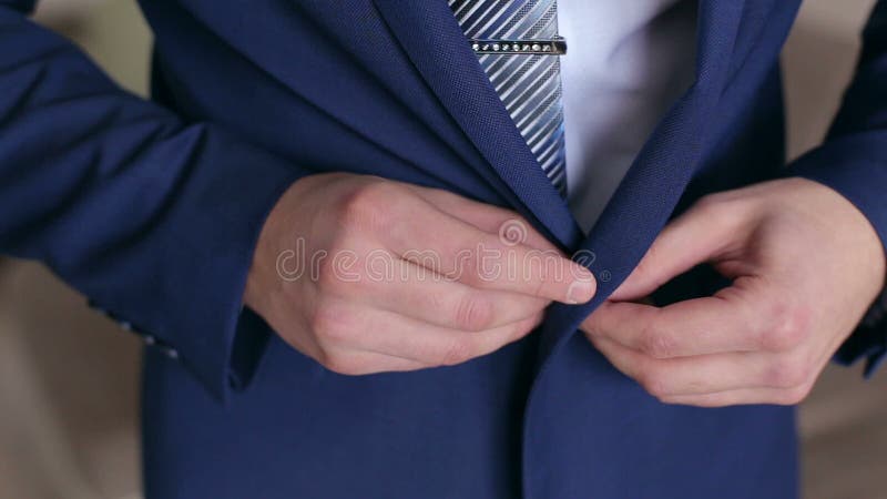 供以人员按在他的夹克，特写镜头的一个按钮