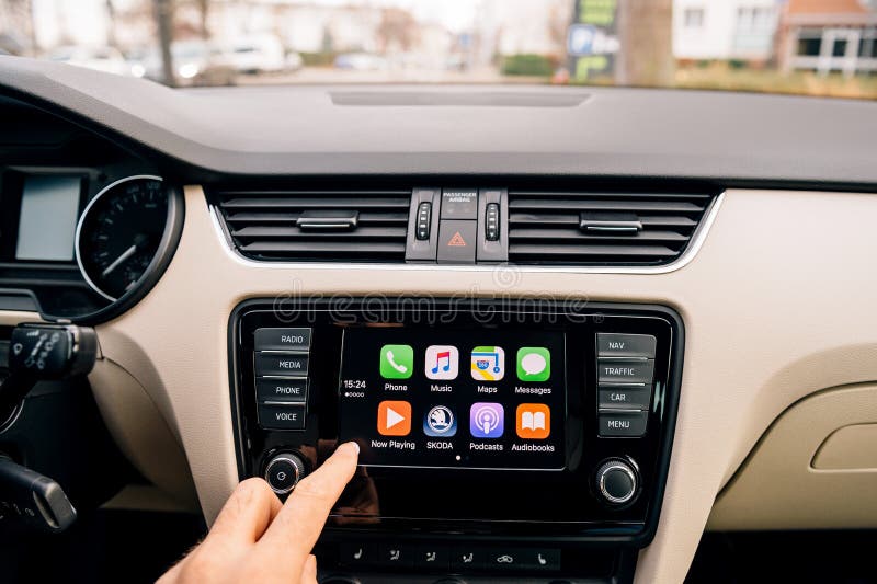 PARIS, FRANCE - DEC 2016: Man pressing home button on the Apple CarPlay main screen in modern car dashboard. CarPlay is an Apple standard that enables a car radio or head unit to be a display and controller for an iPhone. It is available on all iPhone 5 and later with at least iOS 7.1. PARIS, FRANCE - DEC 2016: Man pressing home button on the Apple CarPlay main screen in modern car dashboard. CarPlay is an Apple standard that enables a car radio or head unit to be a display and controller for an iPhone. It is available on all iPhone 5 and later with at least iOS 7.1.