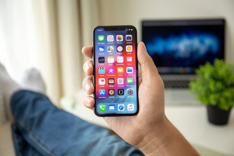 Alushta, Russia - July 29, 2018: Man hand holding iPhone X with home screen IOS. iPhone 10 was created and developed by the Apple inc. Alushta, Russia - July 29, 2018: Man hand holding iPhone X with home screen IOS. iPhone 10 was created and developed by the Apple inc