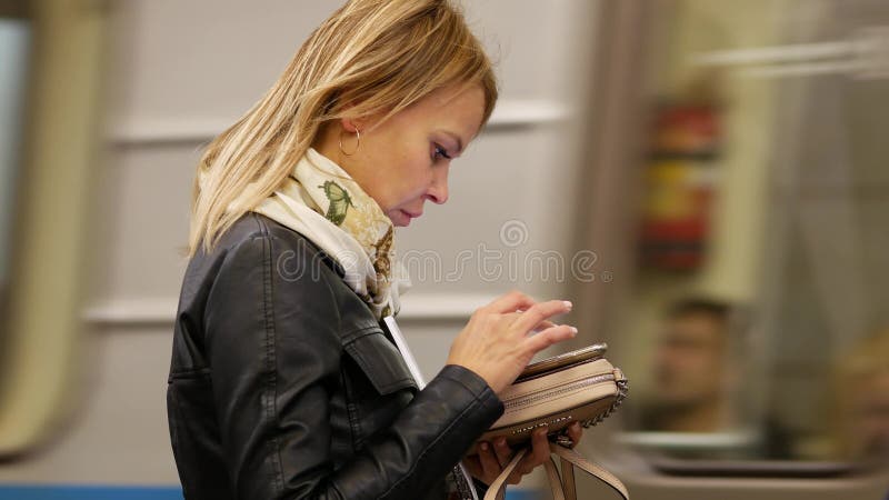 俄罗斯莫斯科 — 2019年10月26日：身穿黑色皮夹克的金发女郎在地铁里用智能手机写信息