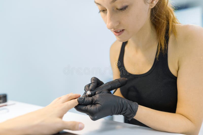 做专业修指甲的年轻微笑的女孩修指甲师 在美容院的钉子和手关心 免版税库存图片 做专业修指甲的年轻微笑的女孩修指甲师 在美容院的钉子和手关心 免版税库存图片