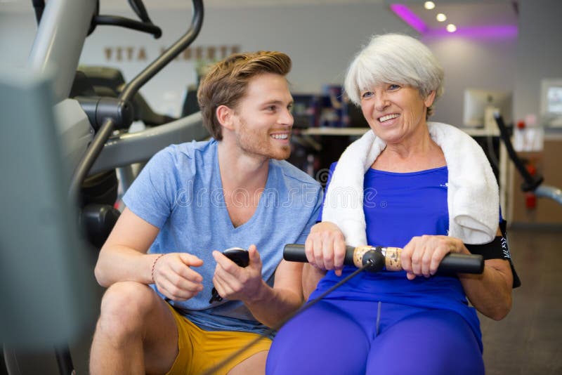 高级女性与教练或私人教练一起做运动 免版税库存图片