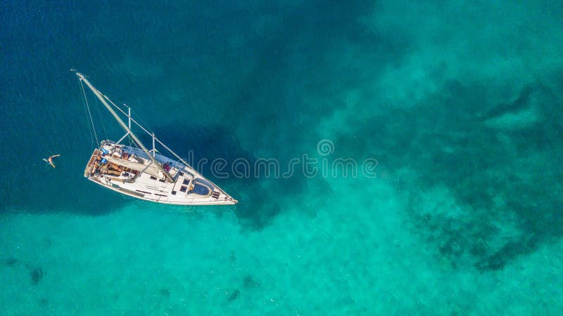 Aerial view of sailing boat anchoring on coral reef. Bird eye view, water sport theme. Aerial view of sailing boat anchoring on coral reef. Bird eye view, water sport theme.