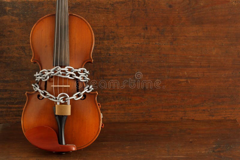 Soul of the music stopped concept: classical violin locked with chain. Soul of the music stopped concept: classical violin locked with chain