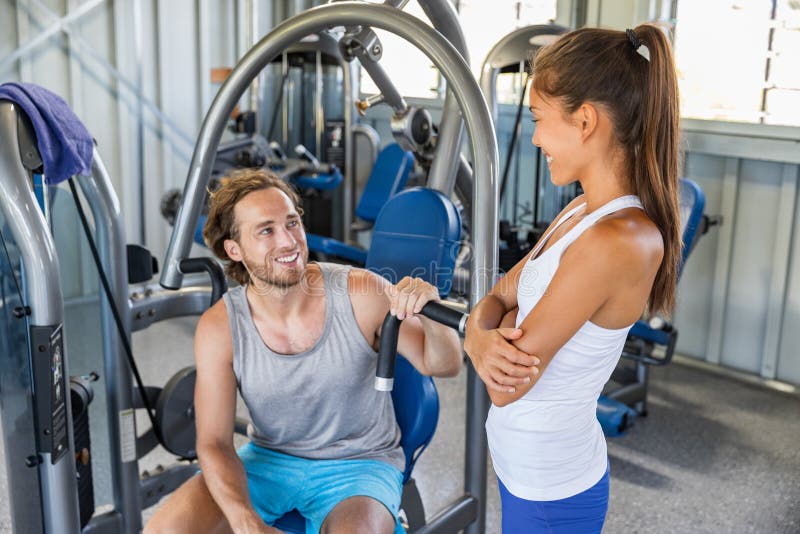健身谈话健身房的教练员供以人员在锻炼设备机器的训练户内 结合愉快解决