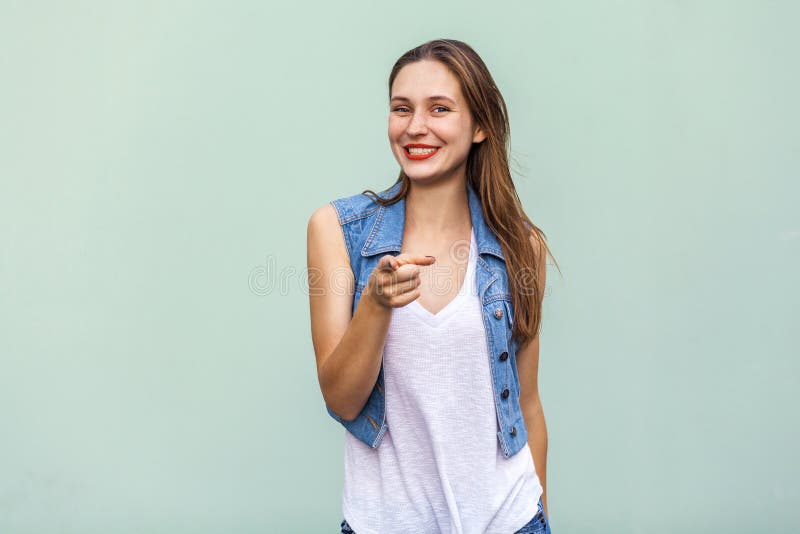 偶然白色T恤杉和牛仔裤jecket的滑稽的有雀斑的女孩,把手指指向照相机和暴牙的微笑 免版税库存图片 偶然白色T恤杉和牛仔裤jecket的滑稽的有雀斑的女孩,把手指指向照相机和暴牙的微笑 免版税库存图片