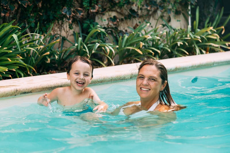 Mom an son get fun into the water in a swimming pool. Summer season in home. Mom an son get fun into the water in a swimming pool. Summer season in home.