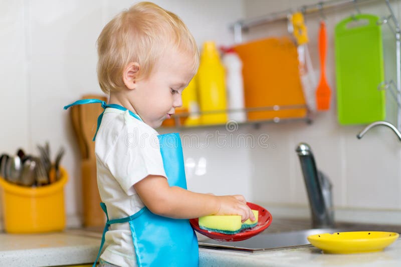 Cute child boy 2 years old washing dishes in kitchen. Cute child boy 2 years old washing dishes in kitchen