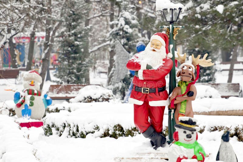 Santa Claus and one of his reindeer alongside a few snowmen in Christmas decorated park in Bucharest. Comic look. Selective focus. Santa Claus and one of his reindeer alongside a few snowmen in Christmas decorated park in Bucharest. Comic look. Selective focus.