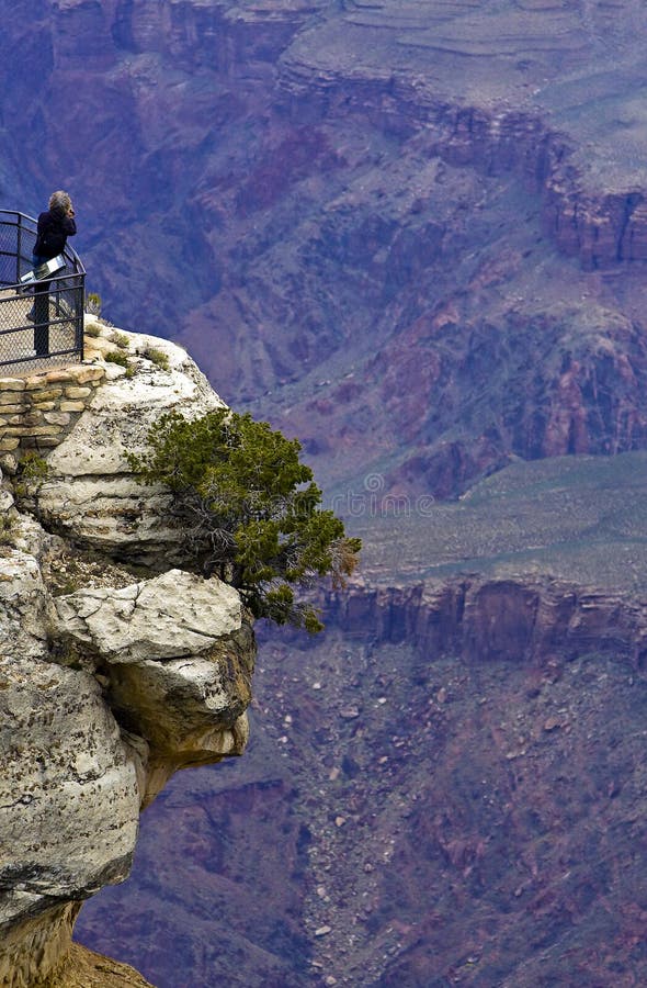 Tourist on a rock on the south rim of the Grand Canyon. Tourist on a rock on the south rim of the Grand Canyon.