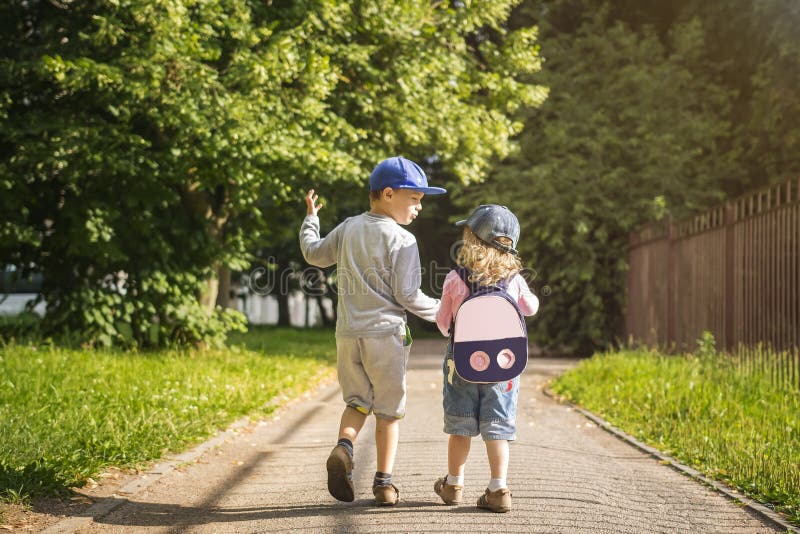  兩個幼兒朋友男孩和女孩在夏天綠色公園舉行手和步行沿路在晴朗的下午 兒童友誼 免版稅圖庫攝影