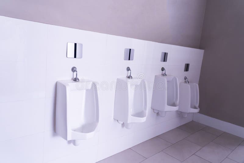 Public restroom. Row of urinals. The urinal design is white ceramic. Modern men&#x27;s bathroom. Public restroom. Row of urinals. The urinal design is white ceramic. Modern men&#x27;s bathroom