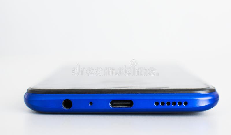 Closeup, USB Type-C charging port, 3.5mm speaker jack, Microphone at the bottom of the blue smartphone on a white background. Closeup, USB Type-C charging port, 3.5mm speaker jack, Microphone at the bottom of the blue smartphone on a white background