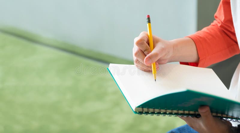 关闭男性少年文字的手与铅笔的在笔记本a