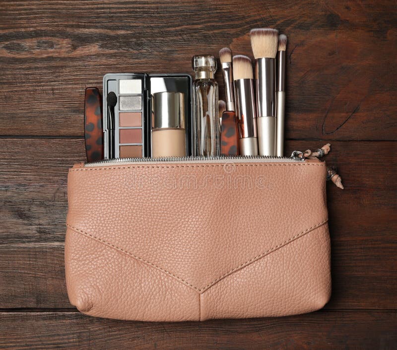 Cosmetic bag with makeup products and beauty accessories on wooden background, flat lay. Cosmetic bag with makeup products and beauty accessories on wooden background, flat lay