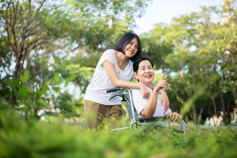 养老保险理念，照顾者要照顾室外坐轮椅的亚洲老年妇女 库存图片