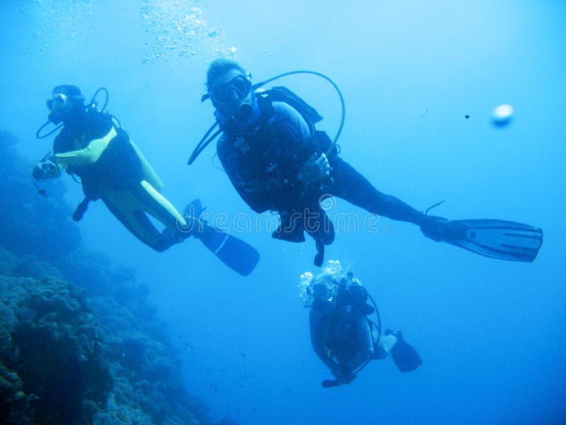 Underwater photo of scuba divers exploring a pristine tropical coral reef on a paradise vacation adventure. Underwater photo of scuba divers exploring a pristine tropical coral reef on a paradise vacation adventure